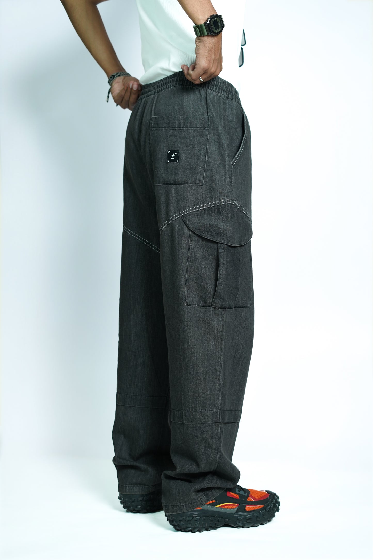 Person wearing dark gray COMEUNITY cargo pants on a white background